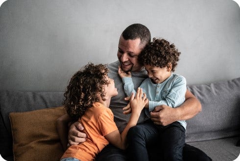 A father laughing with his two children