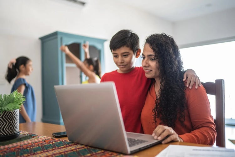 A mother browsing a laptop with her son